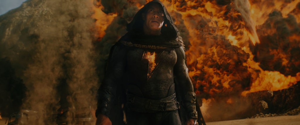 Dwayne "The Rock" Johnson struts in front of explosions in BLACK ADAM (2022)